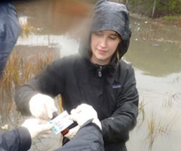 Baykeeper staff member labeling a water sample in the rain