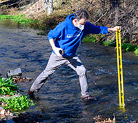 Baykeeper scientist measuring the depth of a creek