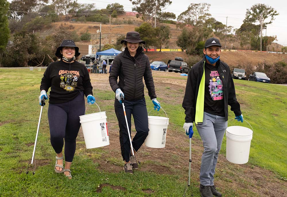 Three cleanup volunteers with buckets