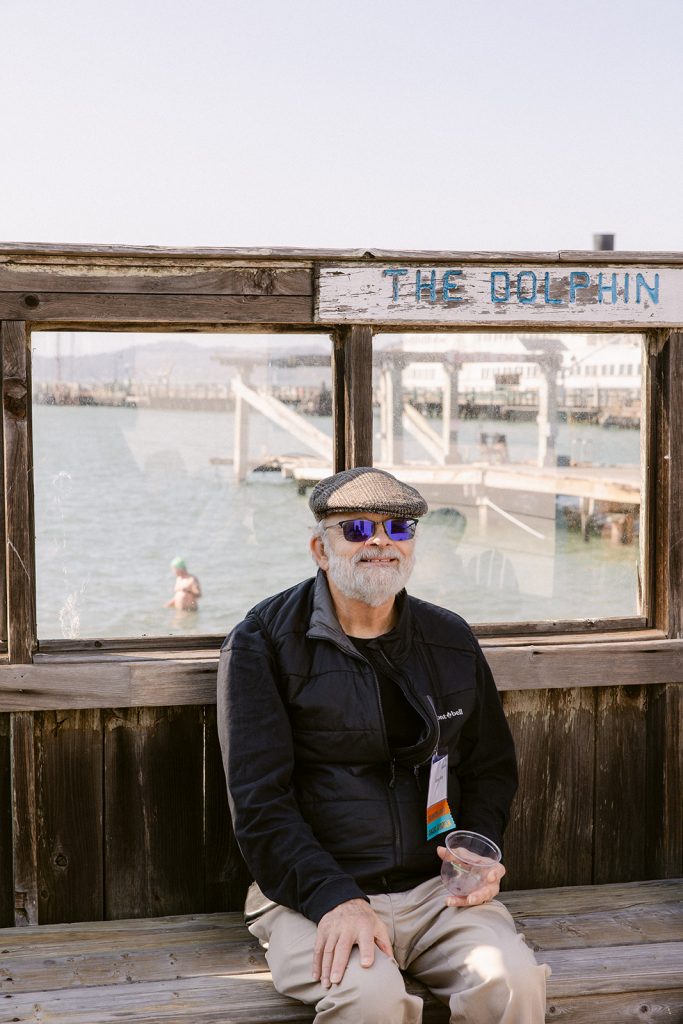 Volunteer Randy Roig sitting outdoors at the Dolphin Club with Bay in background