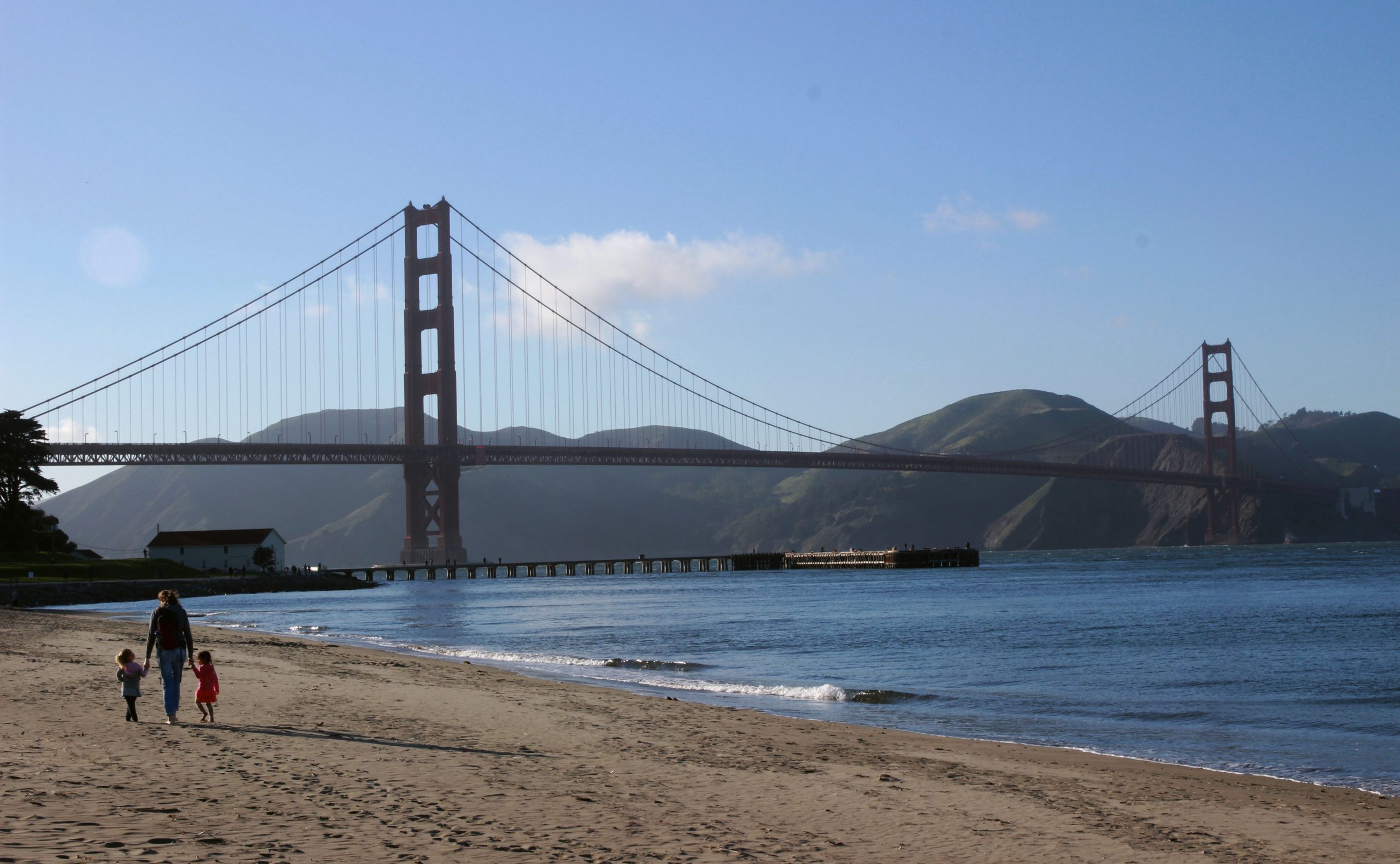 A mother with her kids walk along on the beach near SF Golden Gate bridge on a sunny afternoon 
