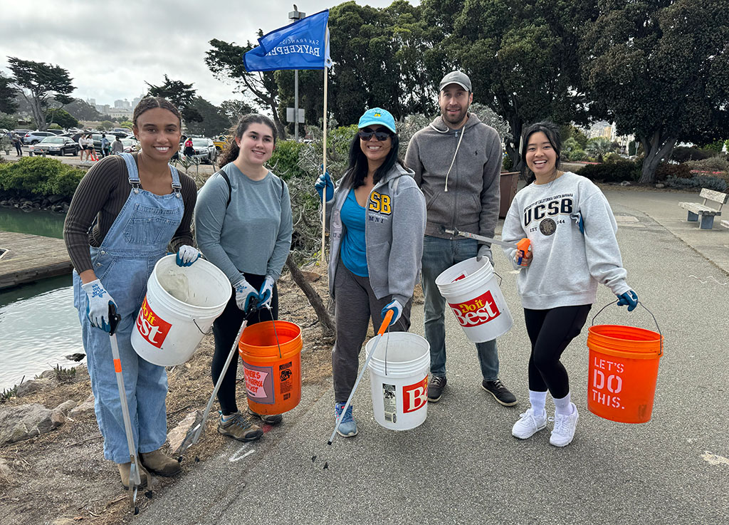 Group of cleanup volunteers with buckets of trash along the shoreline