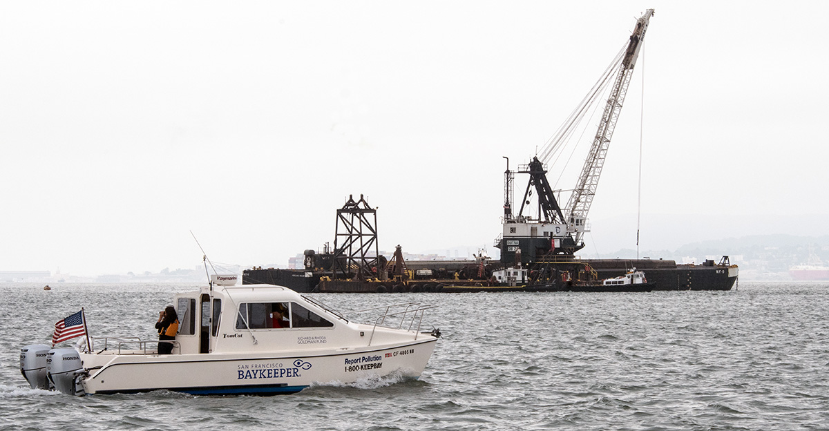 The Baykeeper boat on the Bay with dredgder in the background