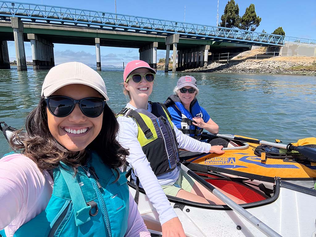 Three staff members on board a kayak and smiling 