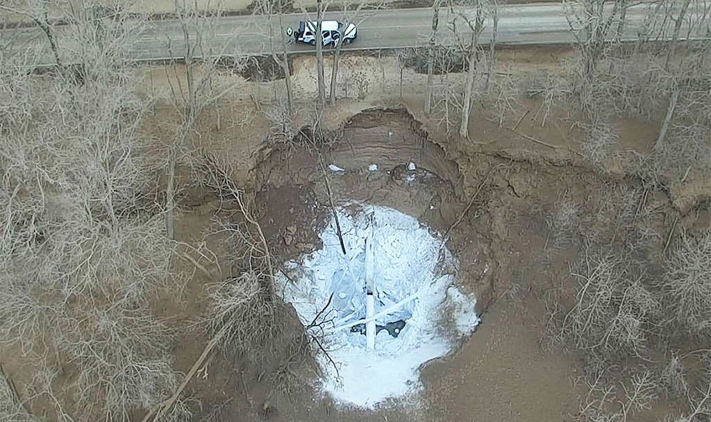 A large hole alongside a road with a white substance
